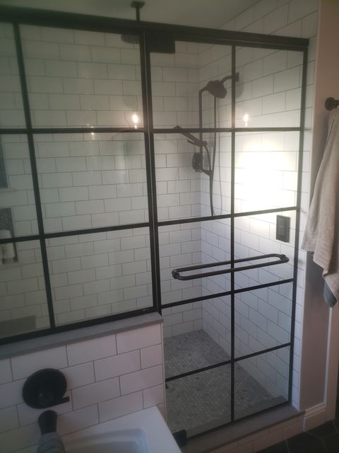 Black grid-pattern glass shower enclosure with a top-and-bottom pivot door