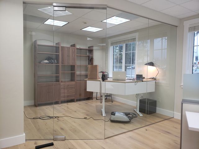 Frameless glass office enclosure with a glass door around a private office