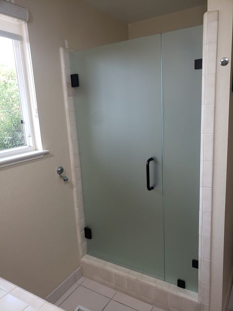 Frosted frameless shower door with black hardware