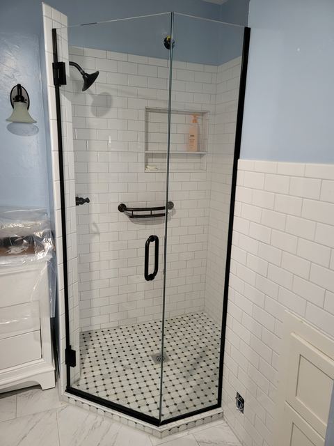 Frameless neo-angle shower enclosure with black hardware and white subway tile