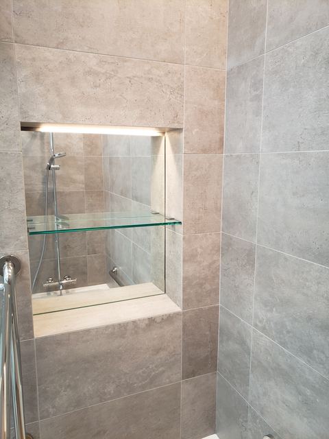 Custom glass shelf in a lit shower niche