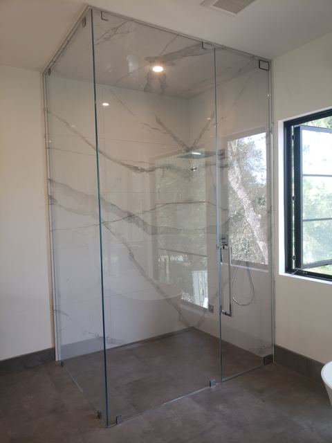 Frameless pivot door shower enclosure with a side panel and ceiling-height glass