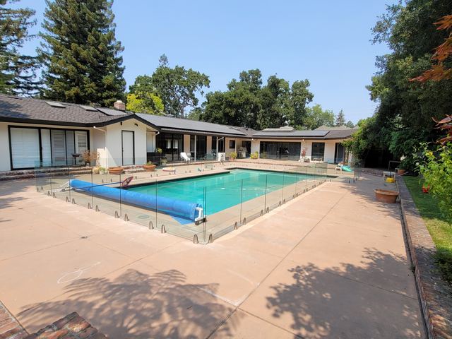 Frameless glass pool railing around a backyard pool
