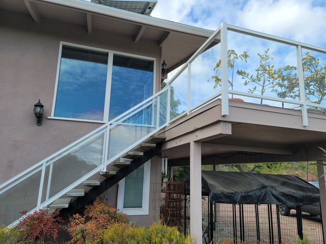 Glass railing with white frame along an exterior stair and deck