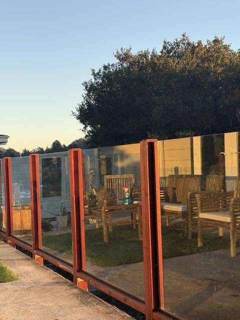 Glass deck railing panels between red posts