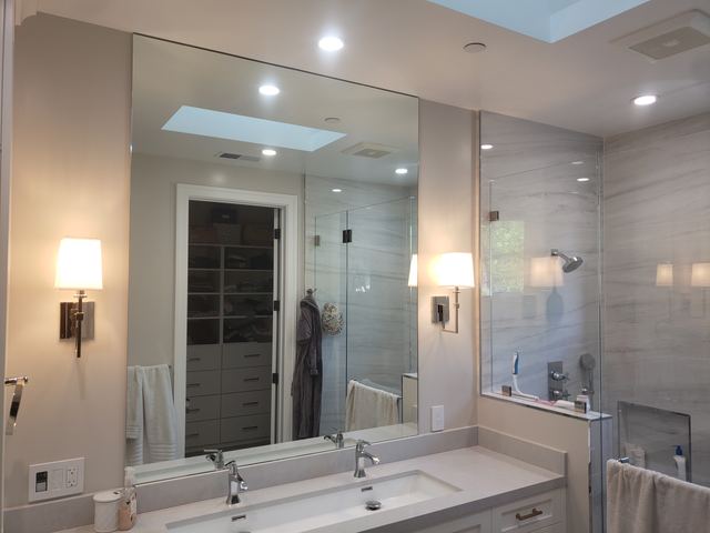 Large mirror over a double sink vanity beside a glass shower enclosure