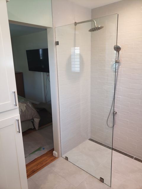 Frameless walk-in shower glass panel with rain shower head